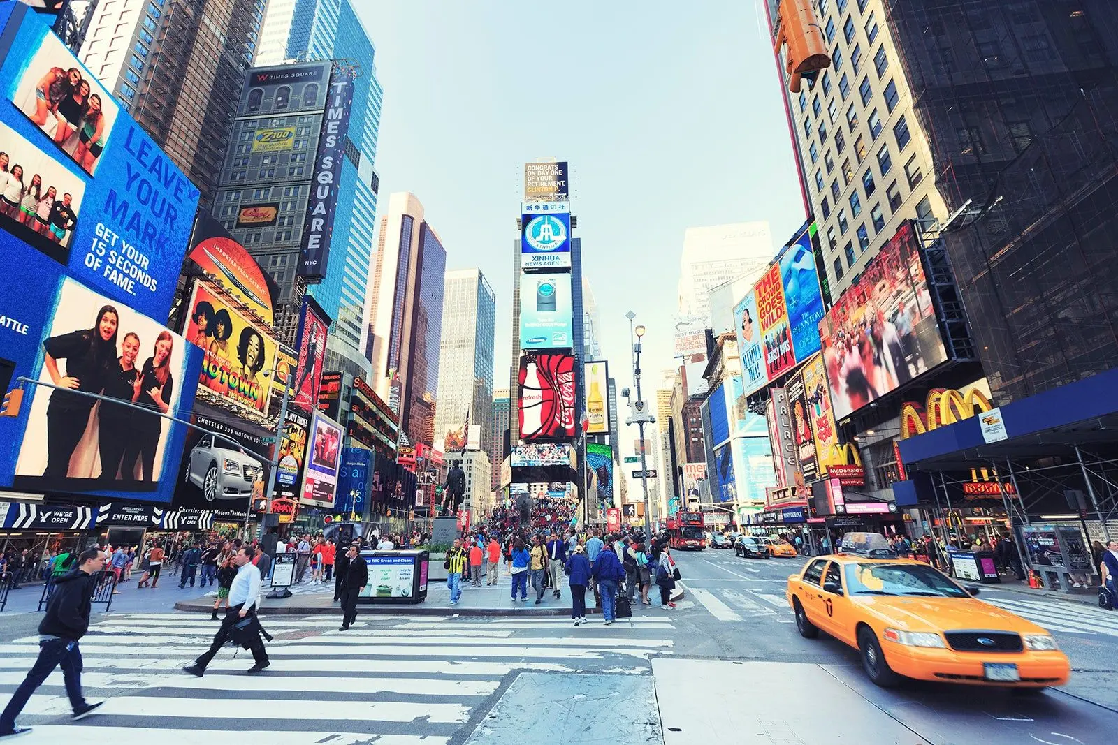 Cruzamento de pedestres e táxis na Times Square durante o dia